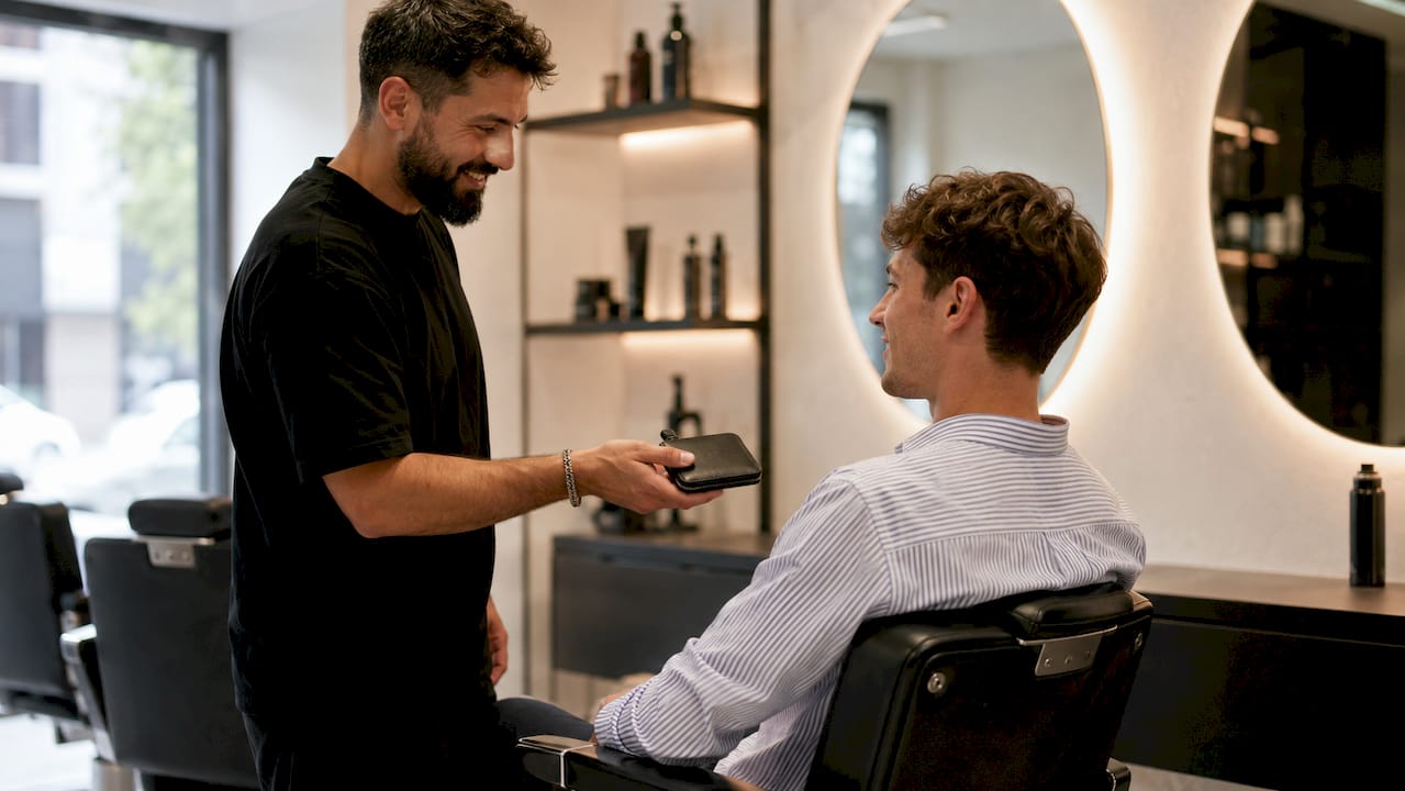 Der Friseur wartet nach dem Haarschnitt darauf, Trinkgeld vom Kunden zu bekommen.