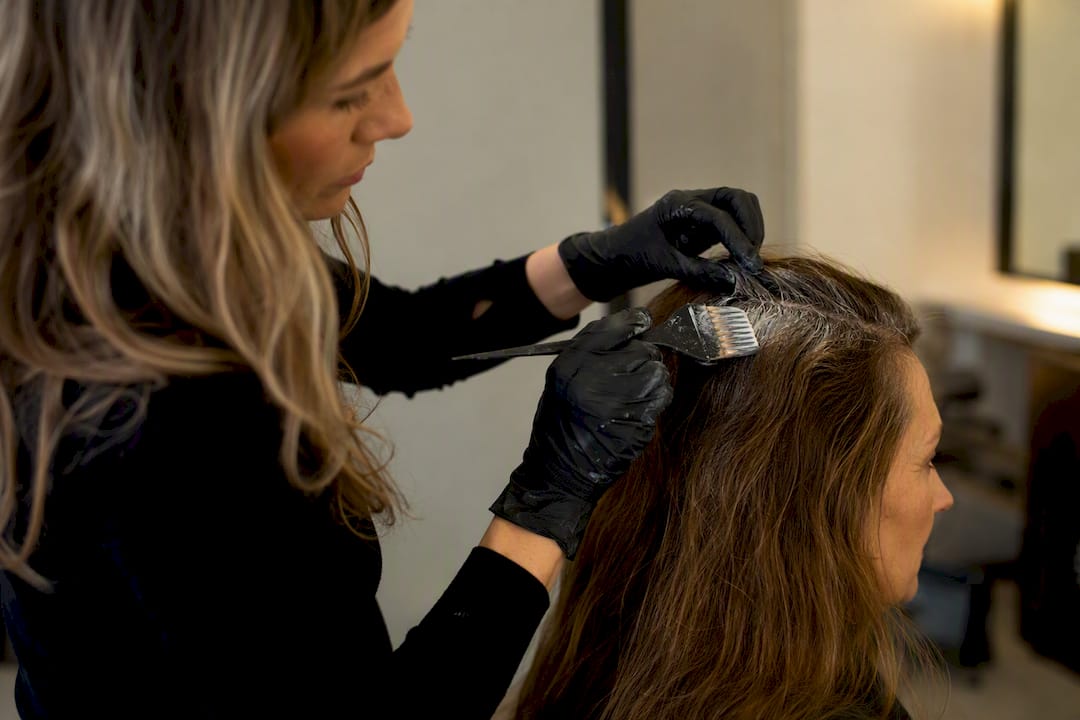 Ein Friseur trägt frische Farbe auf den Haaransatz auf.