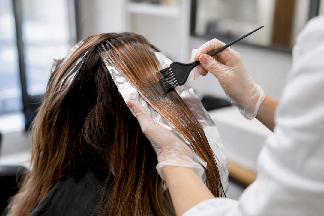 Hände, die die Balayage-Technik mit kupferfarbenem Haarfärbemittel anwenden