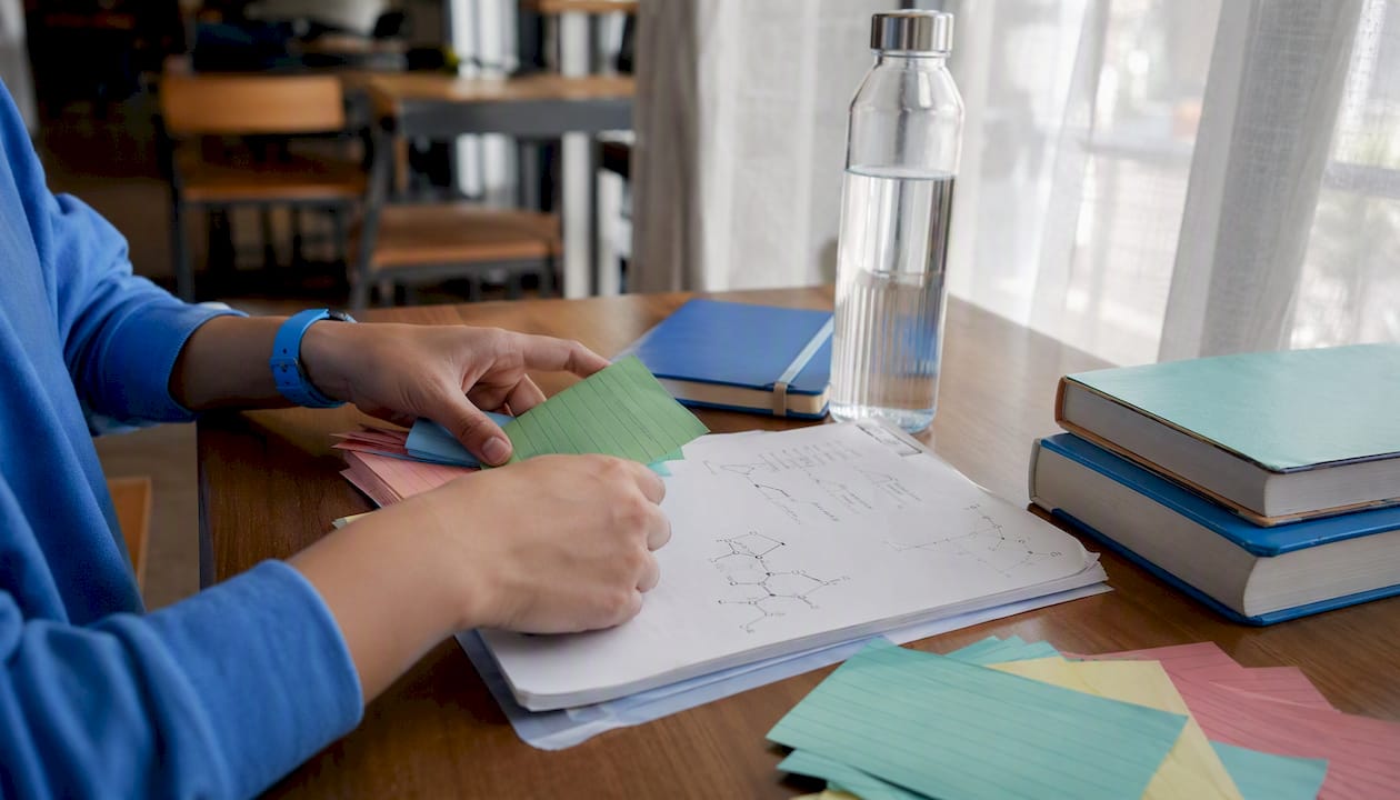 Hands arranging IB Chemistry syllabus cards on table