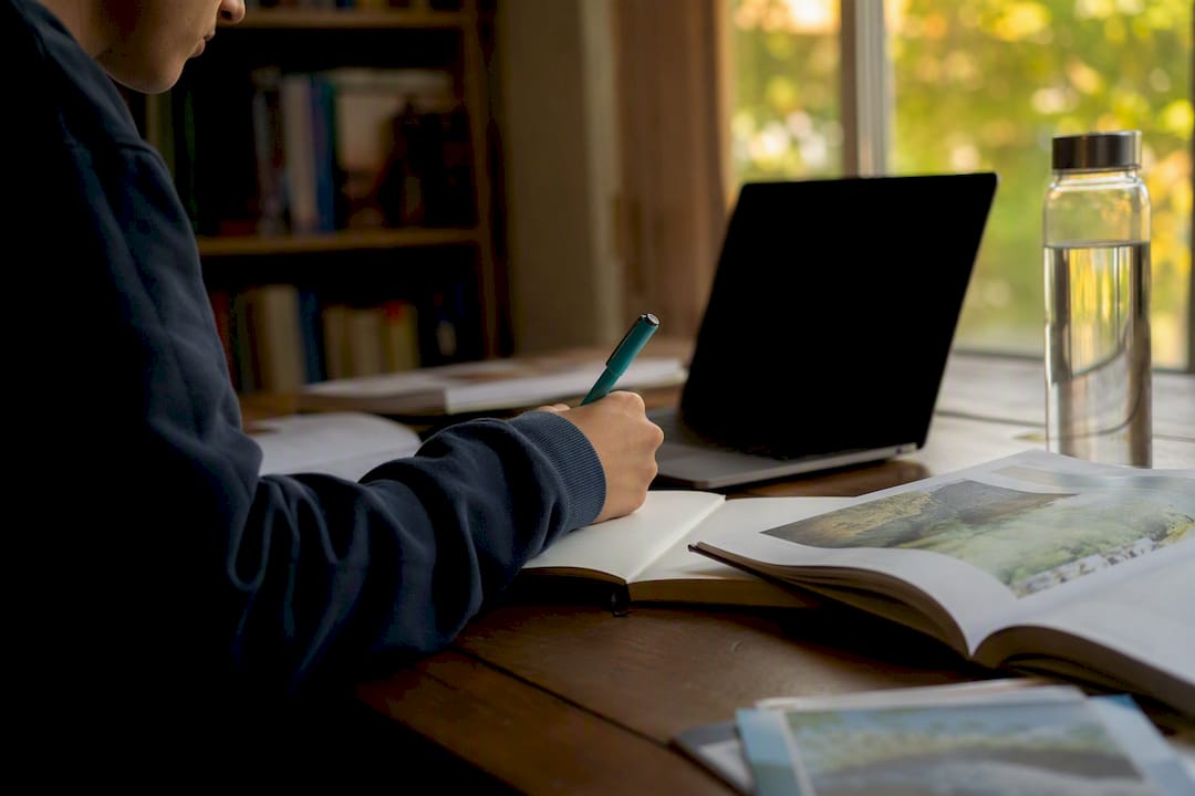 Student hand writing essay notes with pen