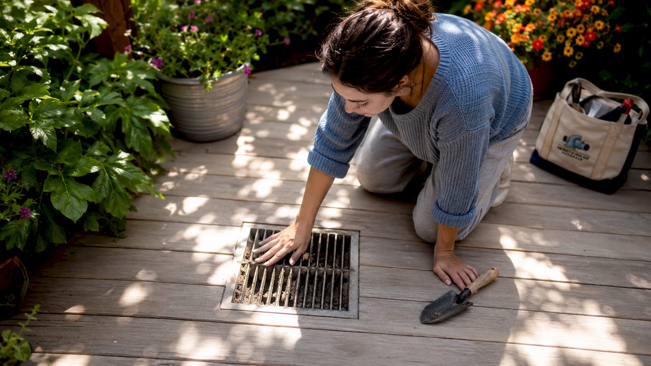Homeowner examining dusty floor air vent