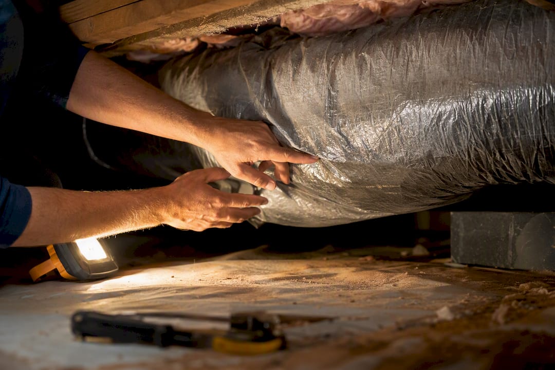 Hands inspecting flexible HVAC duct with sagging