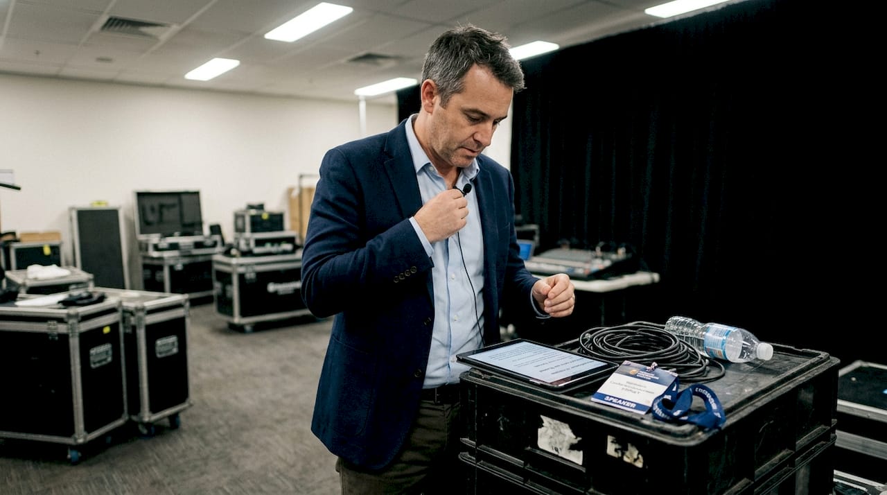 Presenter attaching lapel microphone backstage