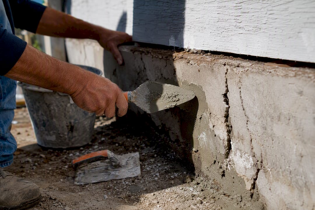 Hands repairing house foundation cracks