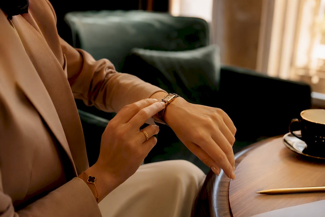 Woman putting on wristwatch near window