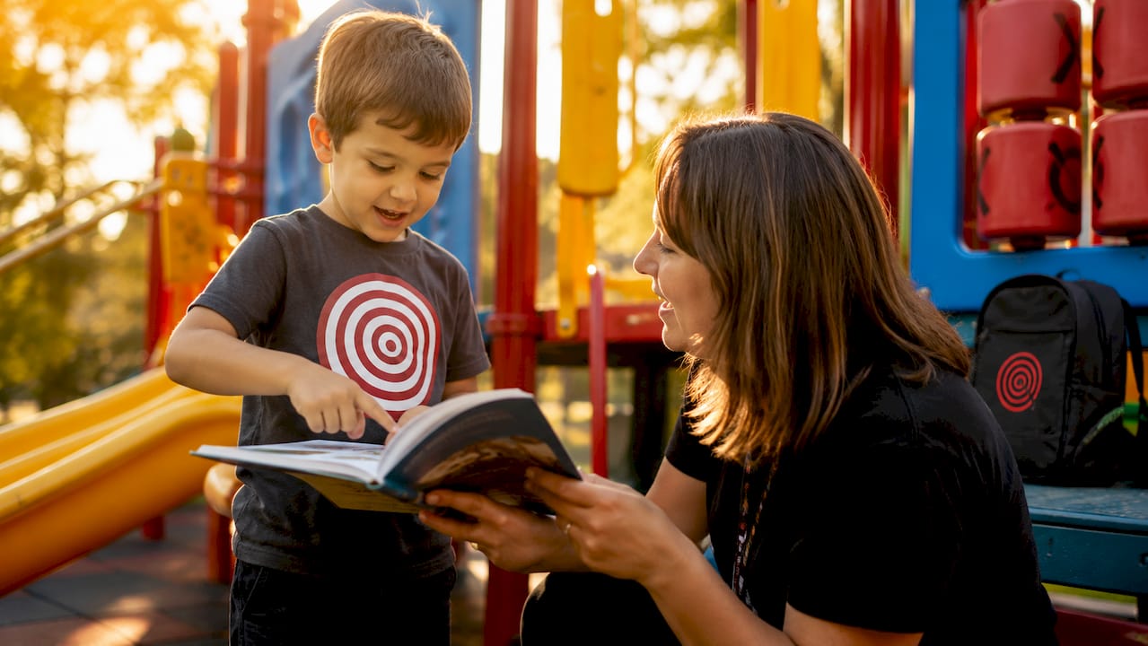 Child reading early chapter book with teacher