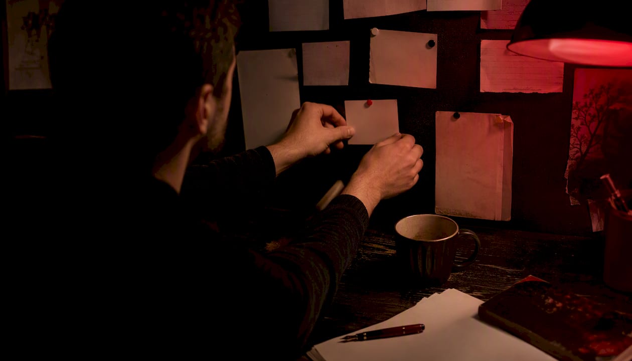 Author pinning horror story seed card at desk