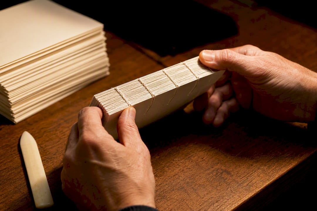 Binder inspecting a newly sewn book block