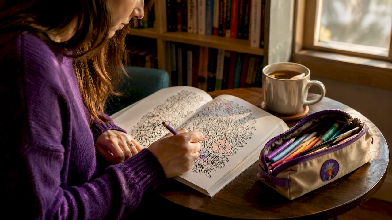 Hands shading floral pattern in coloring book