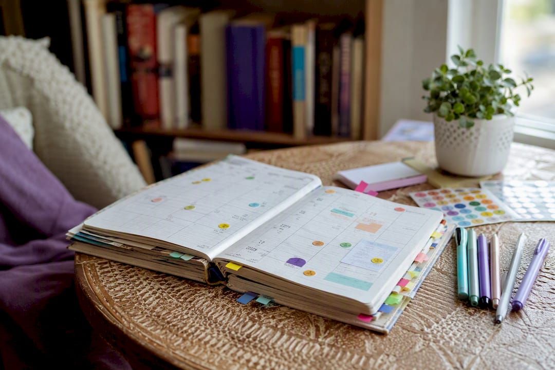 Physical habit planner with colorful stickers and pens
