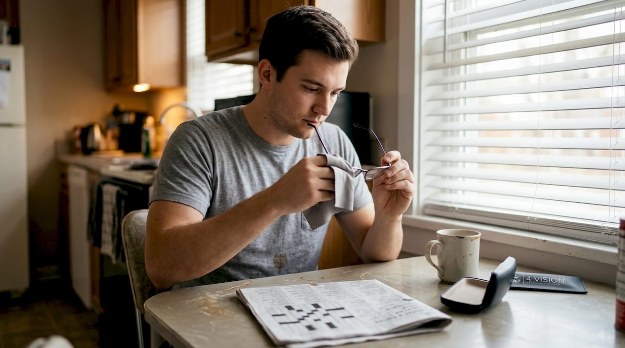 Man cleaning glasses at kitchen table
