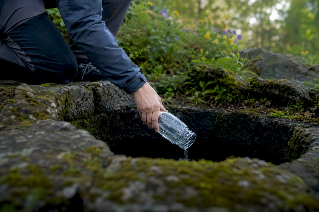 Hand som tar vattenprov från grävd brunn