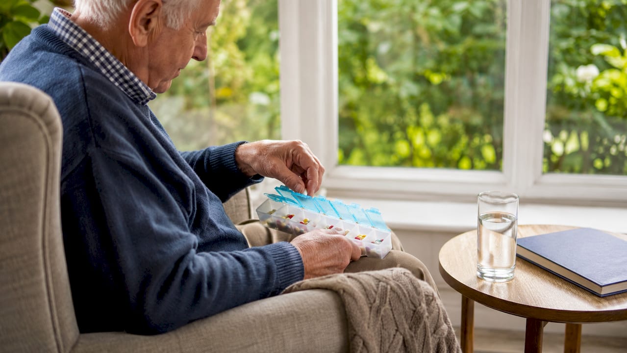 Senior man setting weekly pill organizer