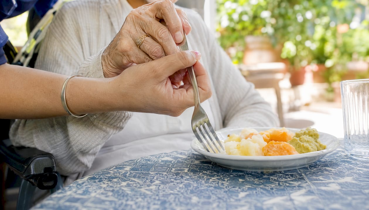 Supporting hands helping dementia patient eat safely