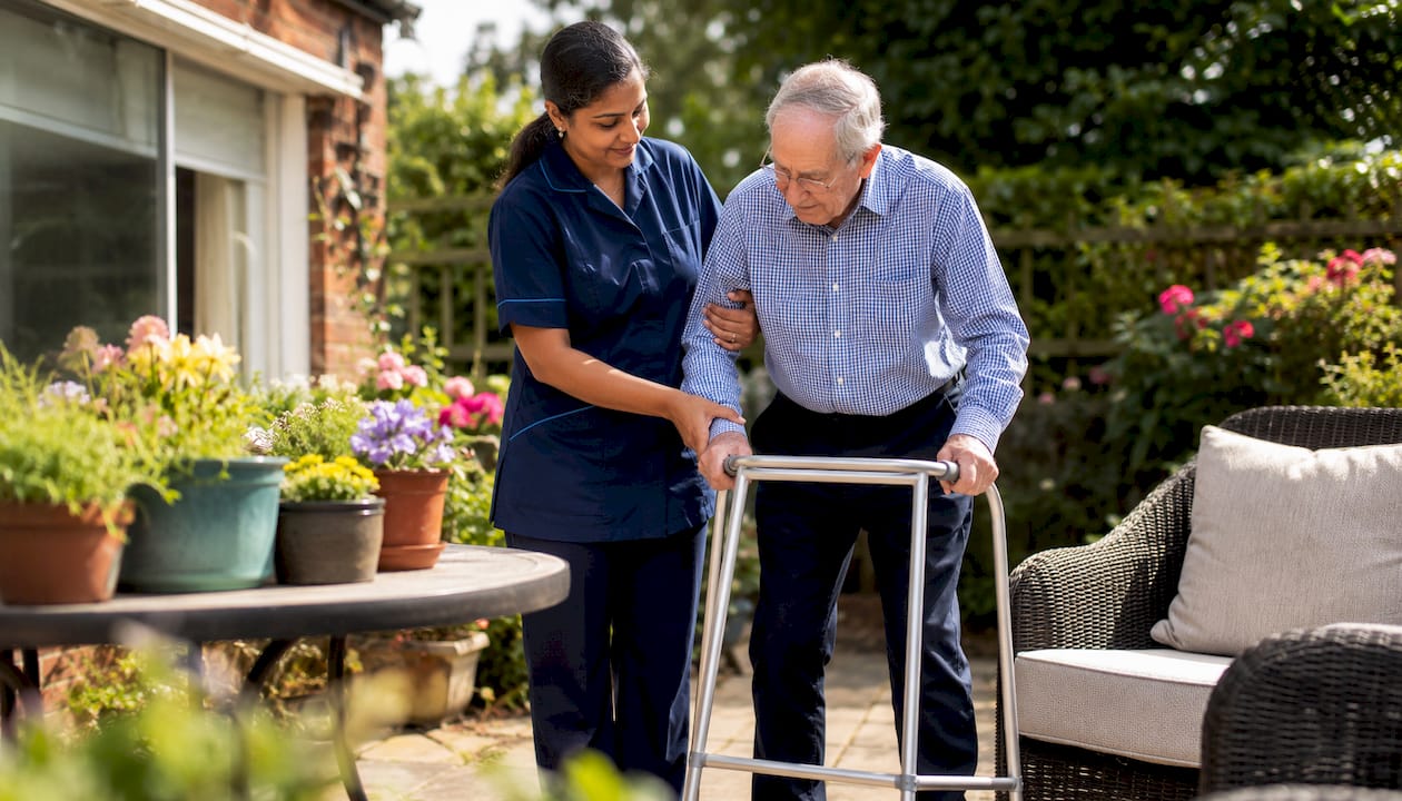 Carer assisting elderly man at home