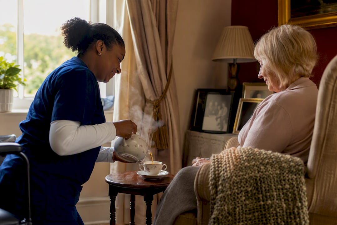 Carer pouring tea in cozy living room