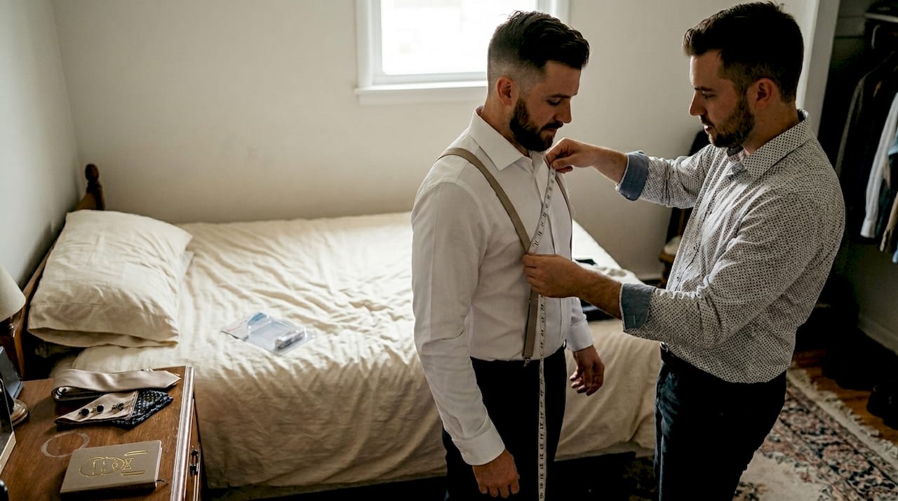 Groom being measured for suspenders