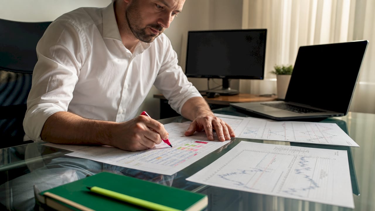 Hands marking forex position sizes on papers