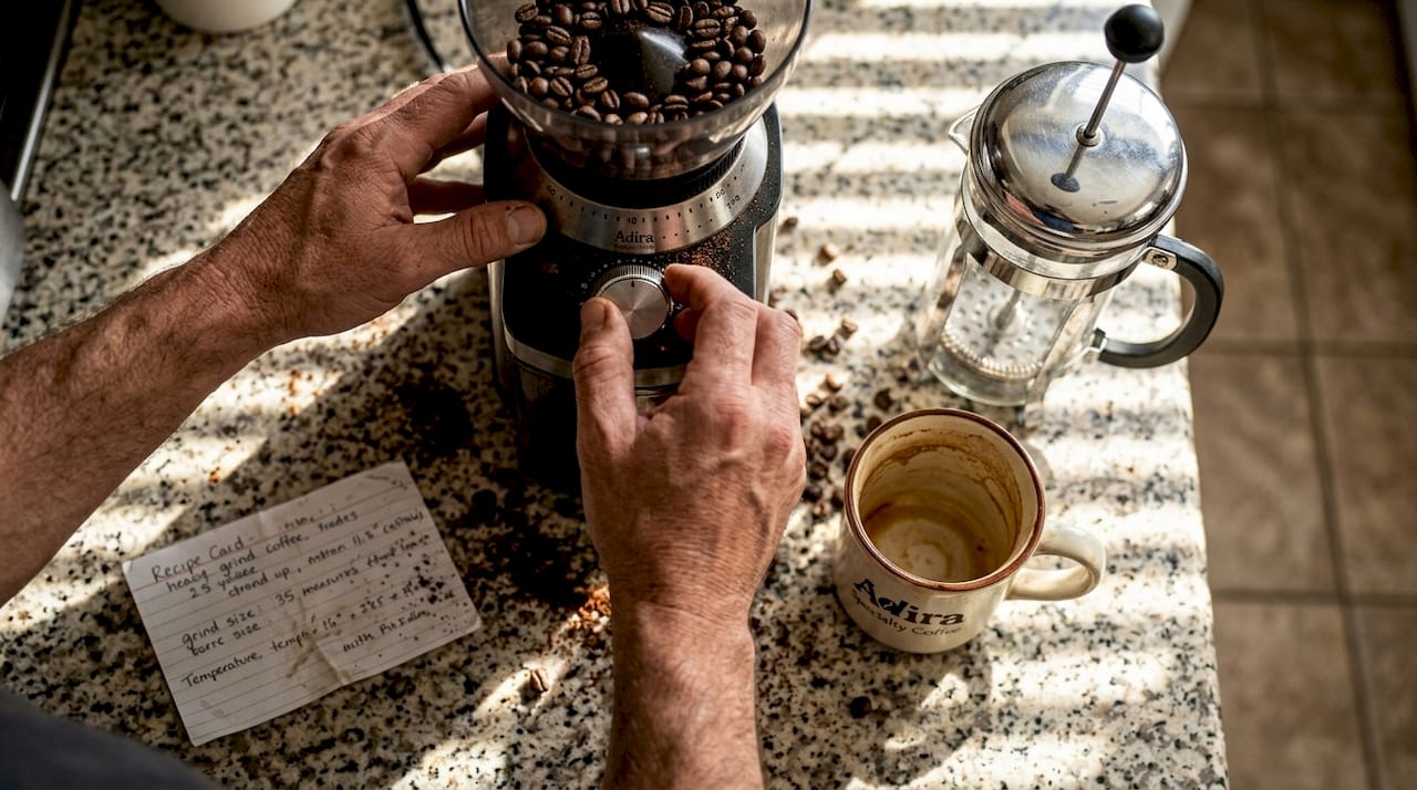Hands adjusting coffee grinder at home