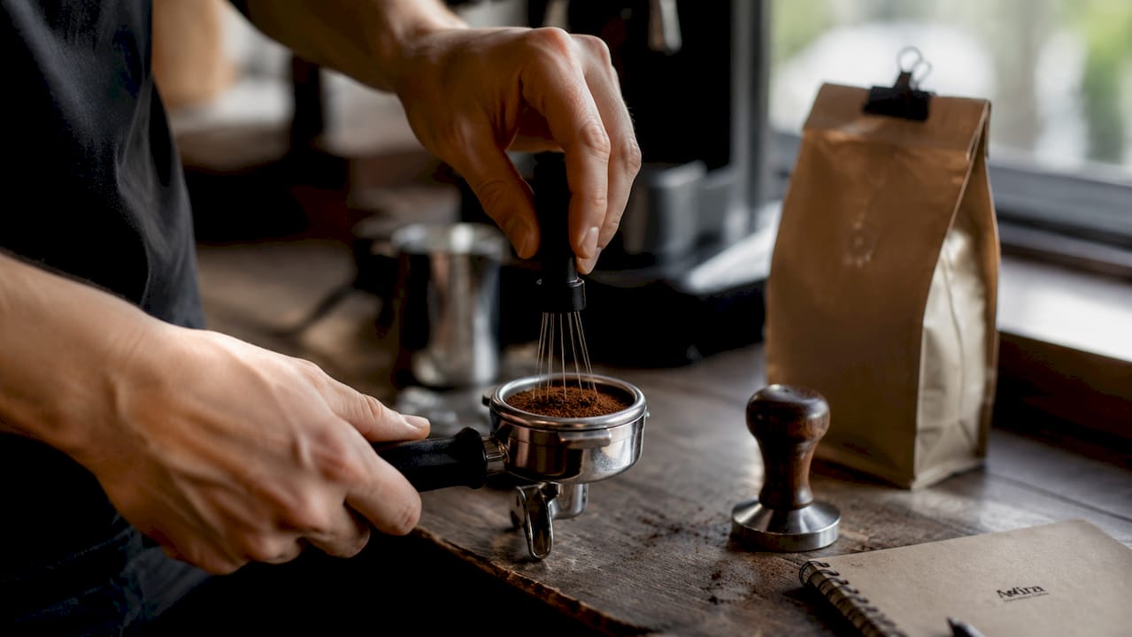 Hands distributing espresso grounds in portafilter