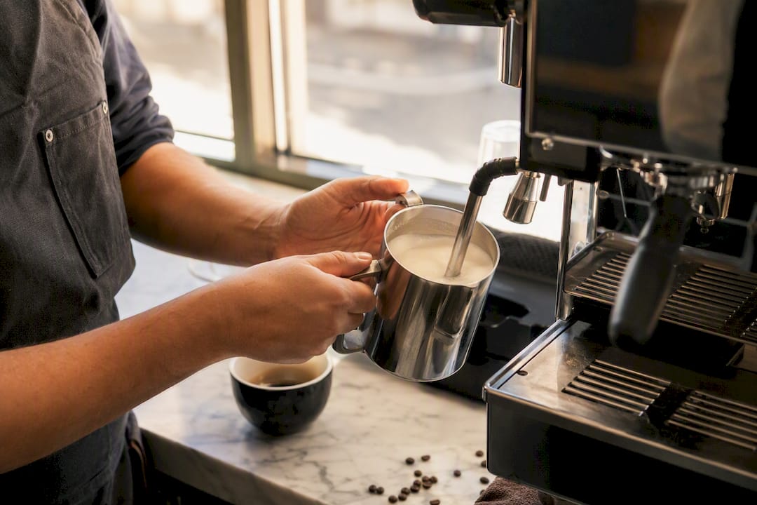 Hands steaming milk with espresso wand