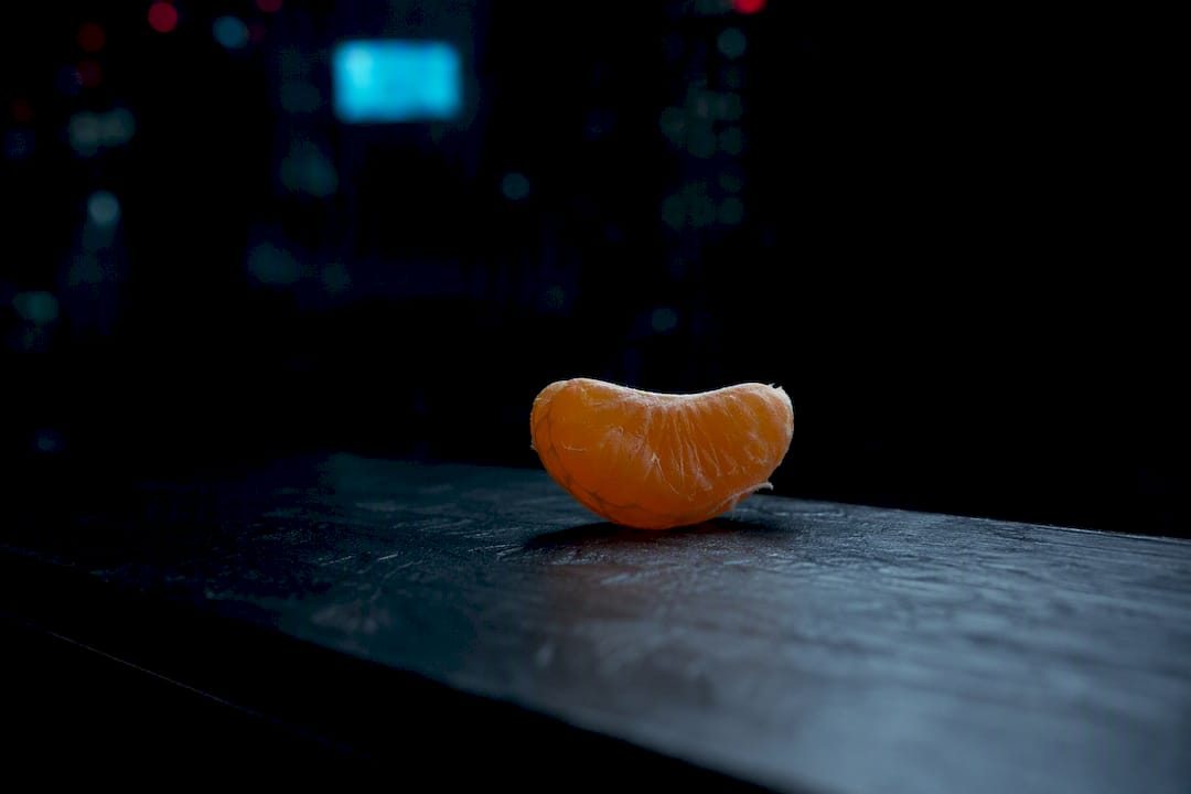 Peeled orange segment glowing in sepia tones