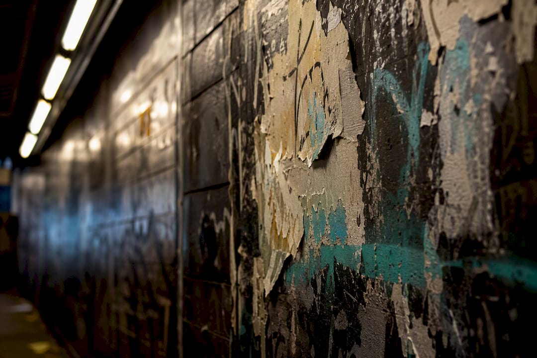 Close-up of subway wall with layered posters and graffiti