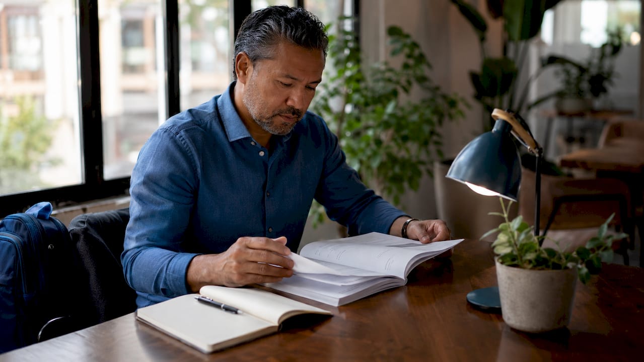 Hands turning pages of payroll compliance manual