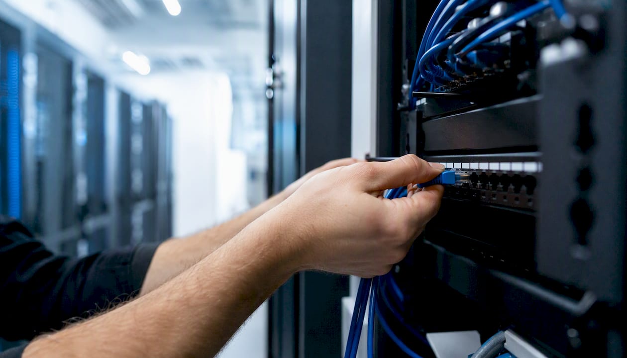 Hands connecting Ethernet cable in server room