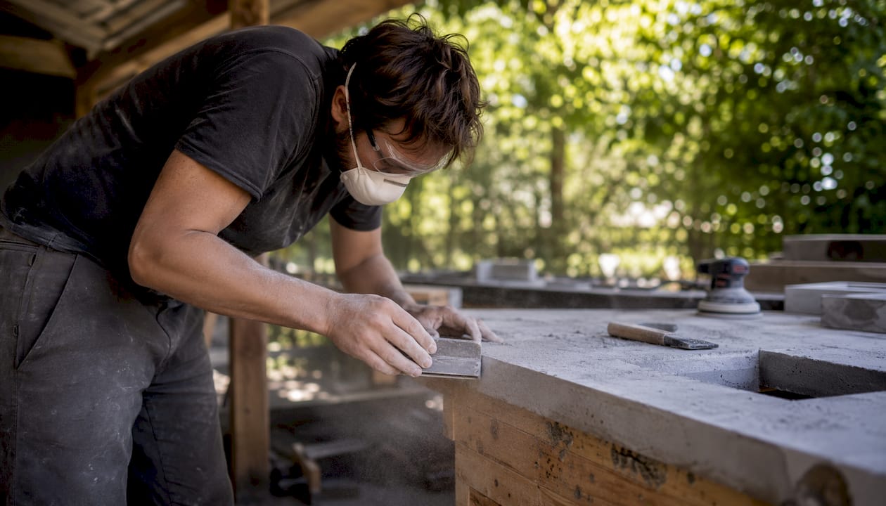 Artisan shaping concrete kitchen countertop in workshop