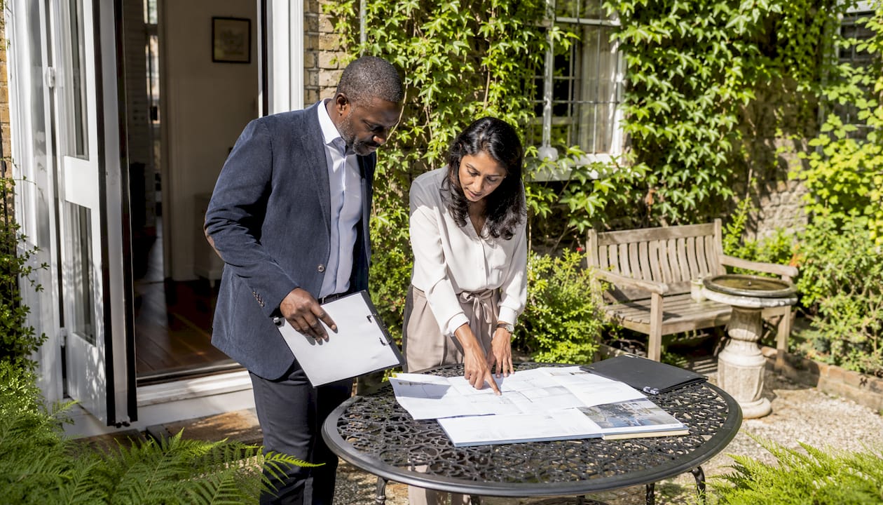 Homeowner and contractor reviewing plans outdoors