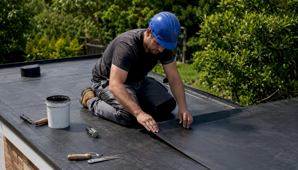 Contractor installing EPDM membrane on flat roof