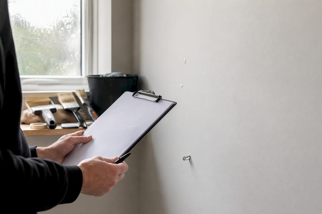 Hands holding snagging checklist on wall