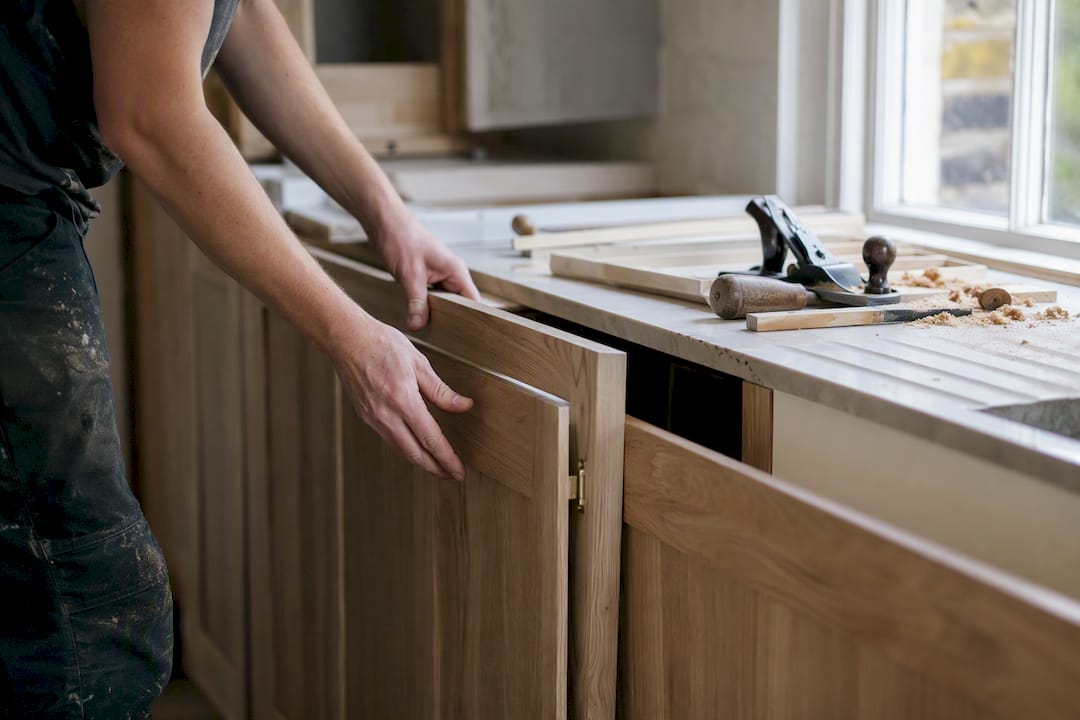 Hands fitting cabinet doors in London kitchen