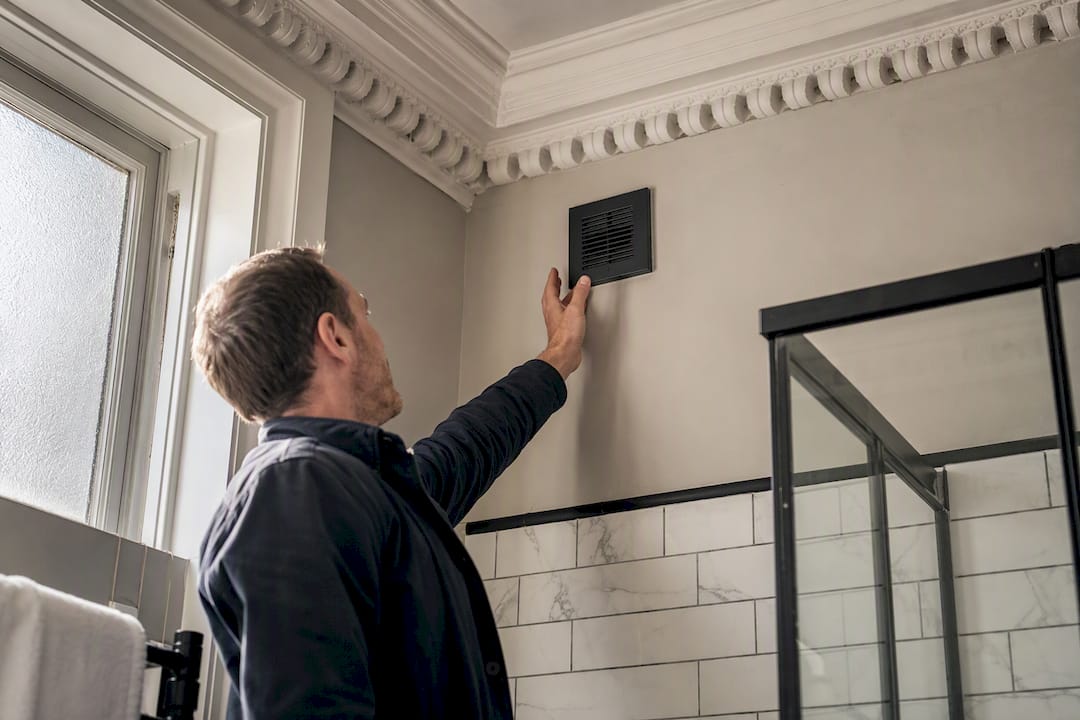 Hand measuring air vent in London Victorian bathroom