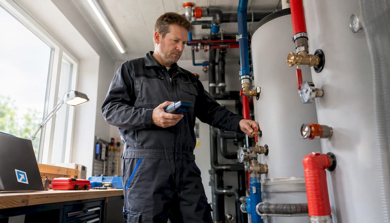 Ein Techniker nimmt den Fernwärmespeicher im Keller genau unter die Lupe.