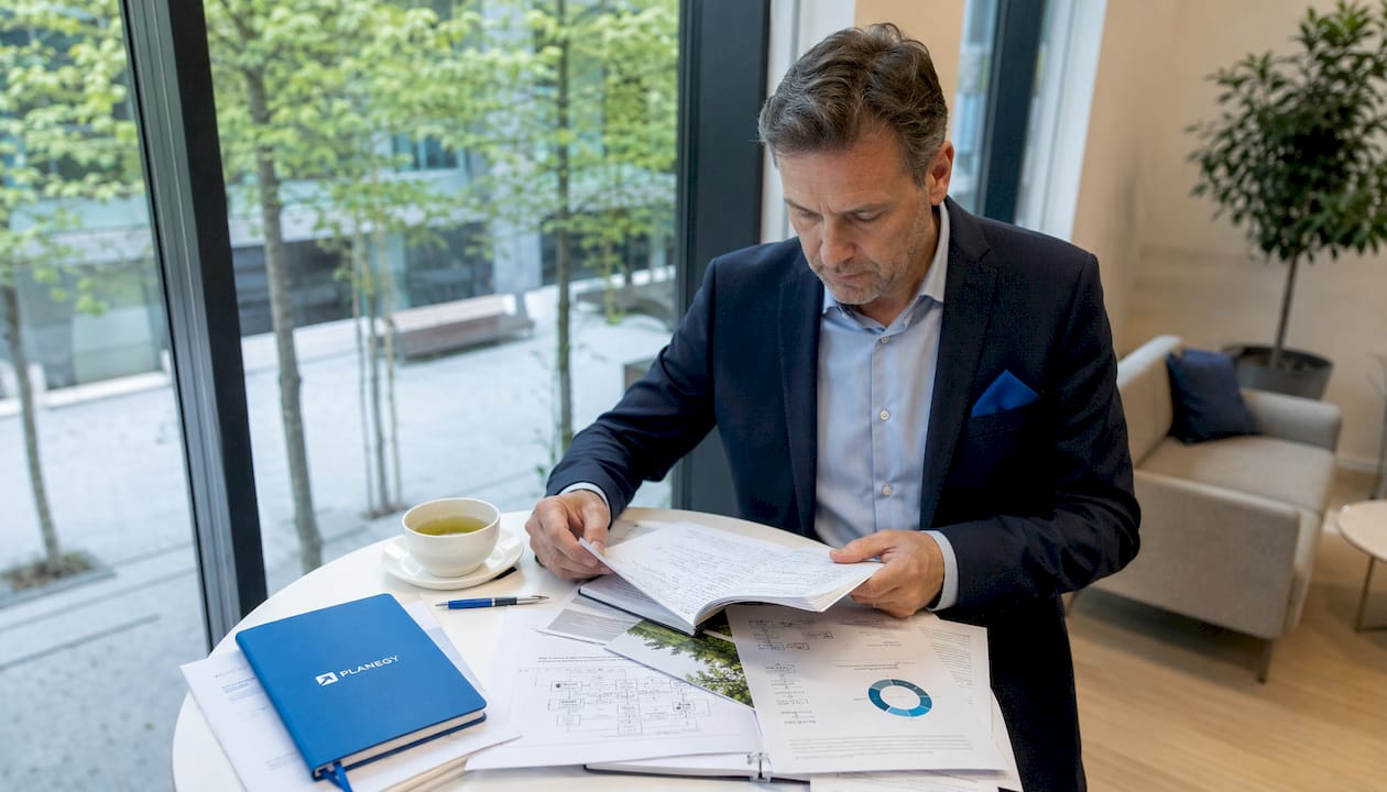 Ein Umweltmanager verschafft sich einen Überblick, indem er die ausgedruckte EMAS-Umwelterklärung sorgfältig durchliest.