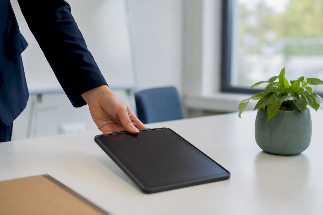 Tablet auf dem Schreibtisch neben einer Pflanze bei Tageslicht