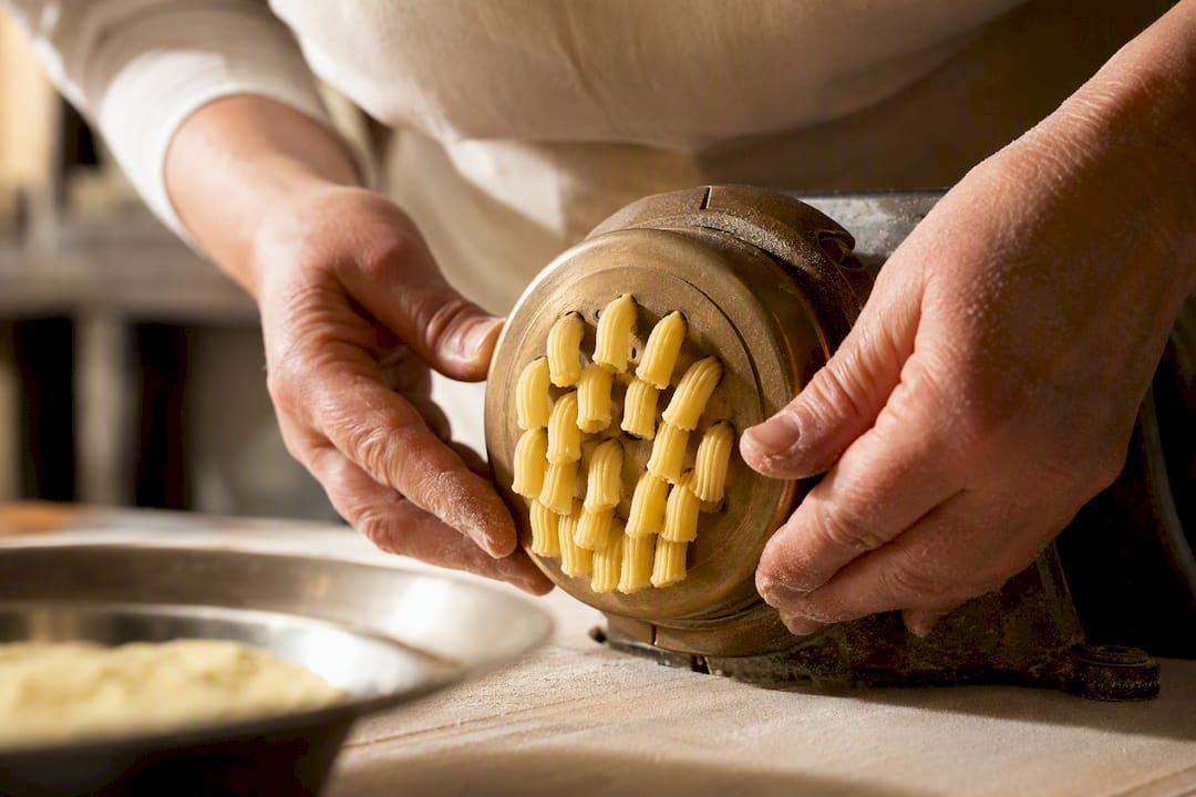 Raue Pasta-Stränge werden durch eine Bronzeform gepresst