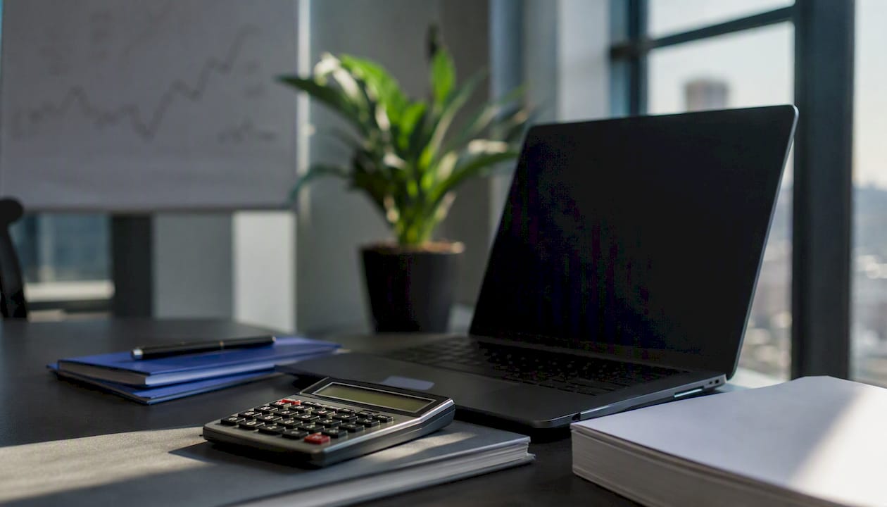Close-up of calculator and dark screen implies trading costs