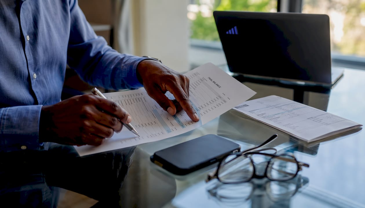 Hands marking trial balance report for errors