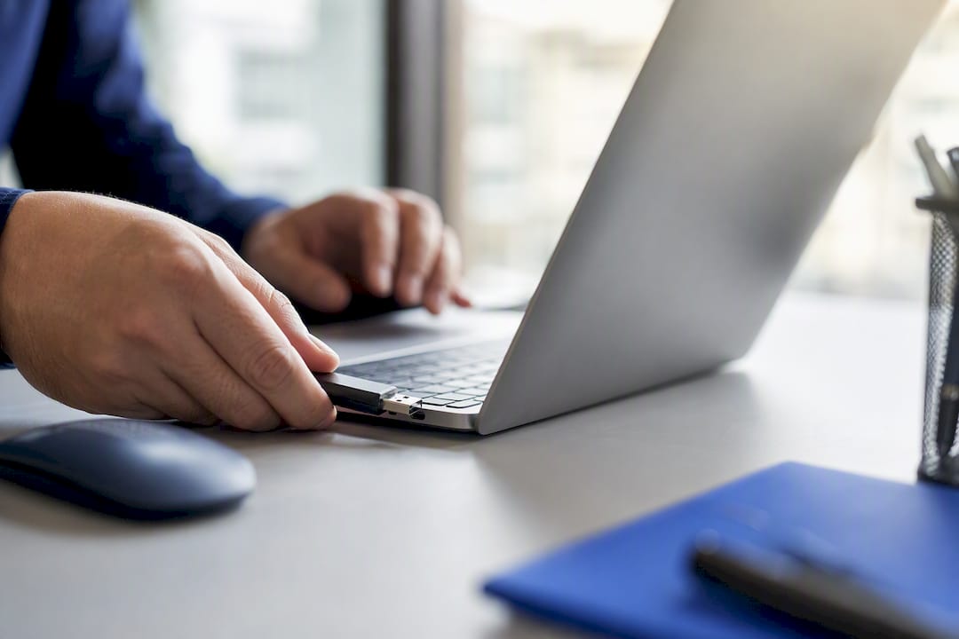 Hands inserting USB security token into laptop