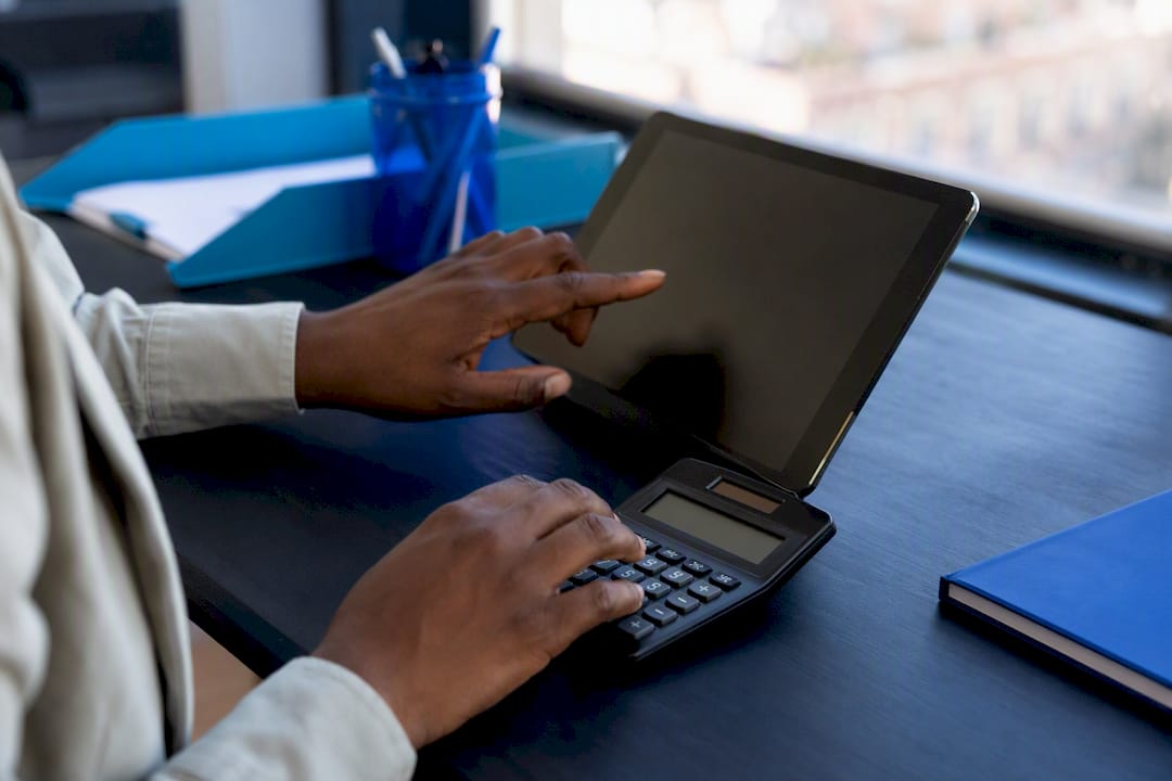 Hands pointing at smartphone and calculator