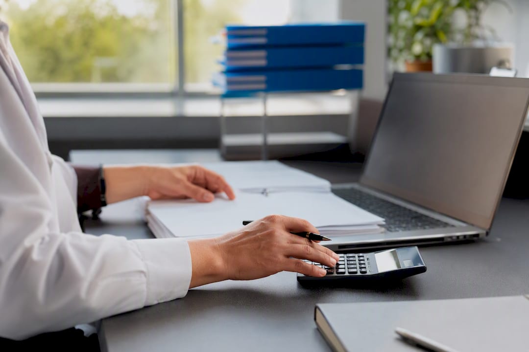 Hands adjusting calculator and ledger pages