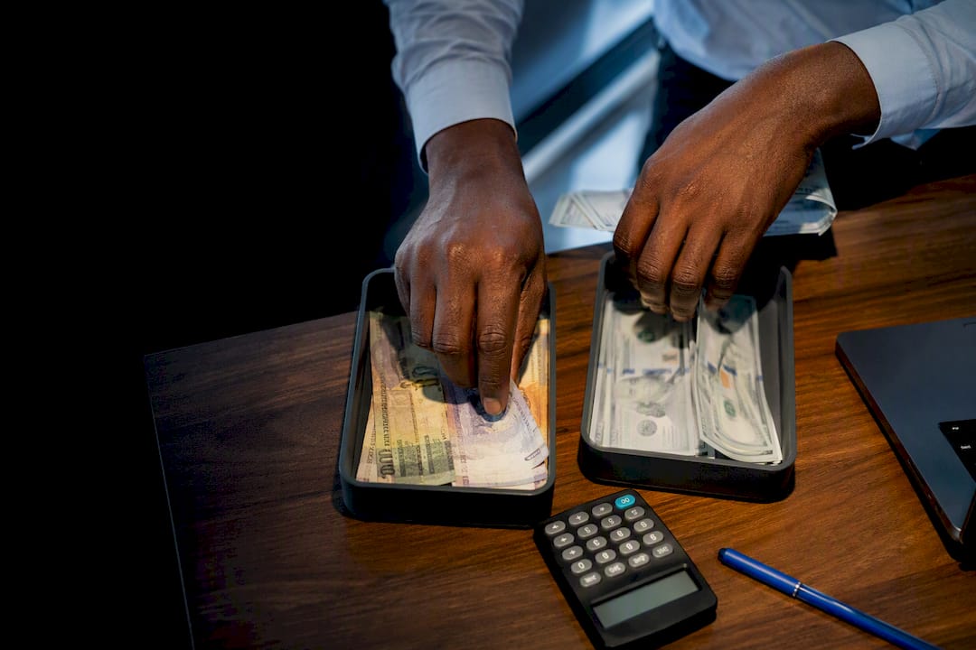 Hands sorting rand and dollar currency