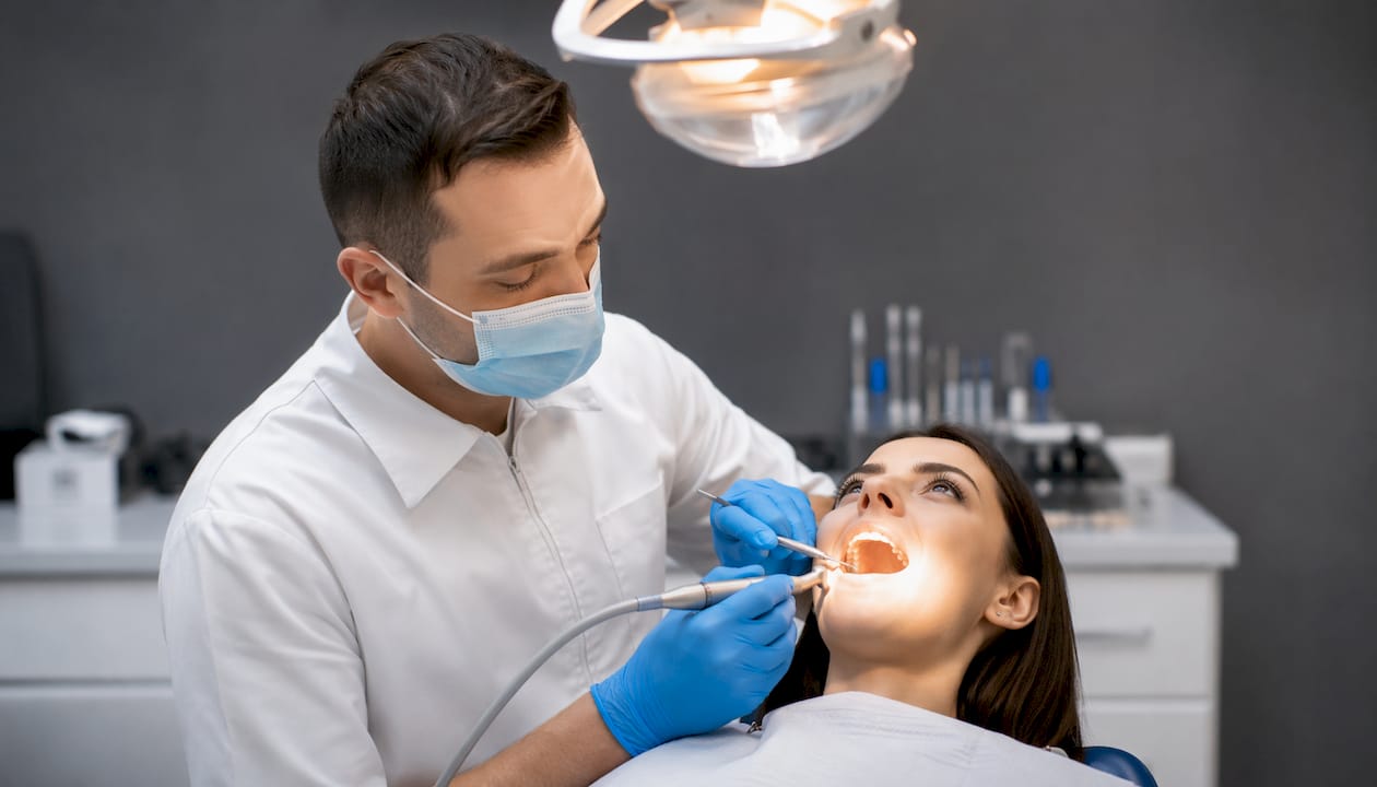 Imagine surprinsă de aproape cu medicul stomatolog în timp ce aplică o plombă din compozit.