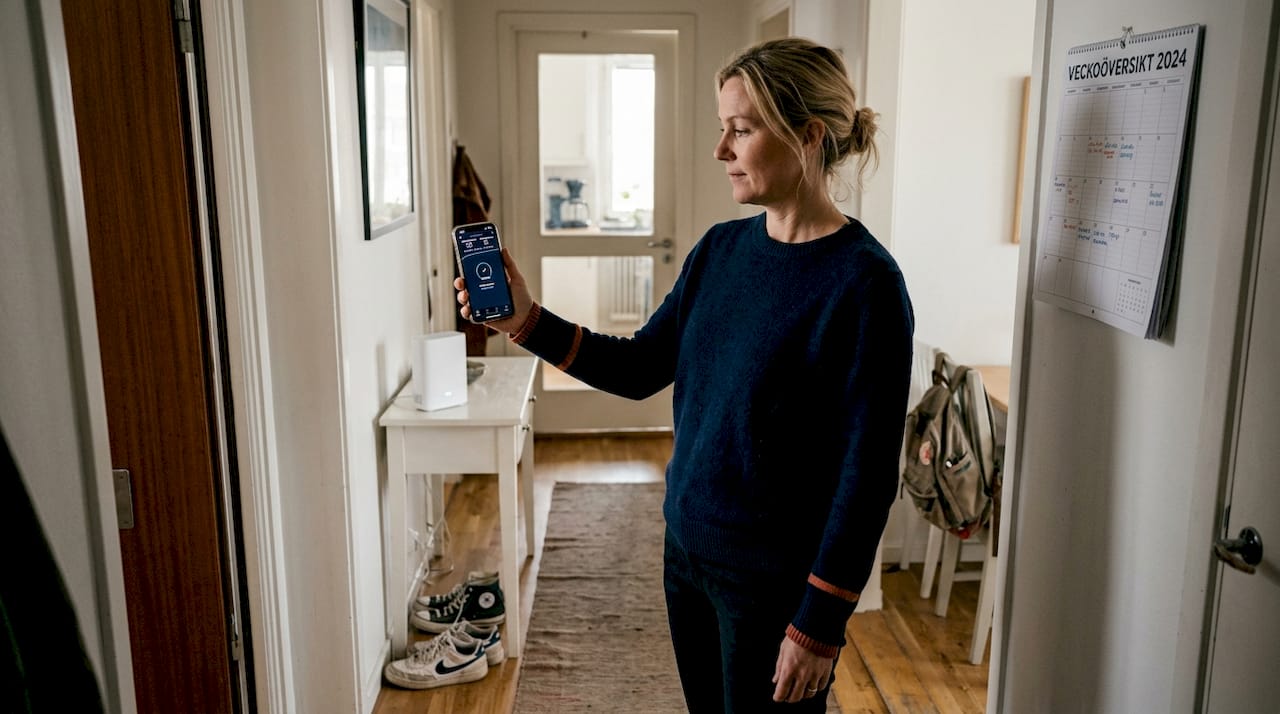 Kvinna kollar hastigheten på sitt wifi bredvid en mesh-router