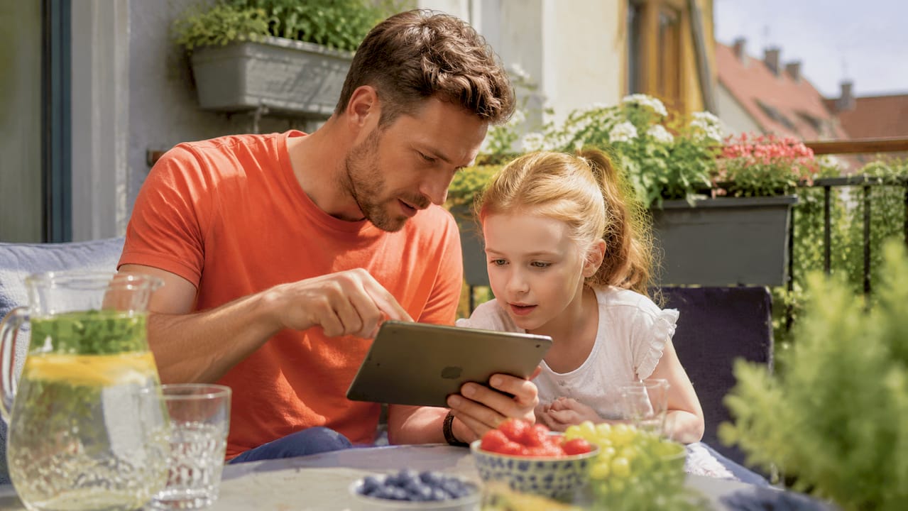 Father and daughter using tech devices together