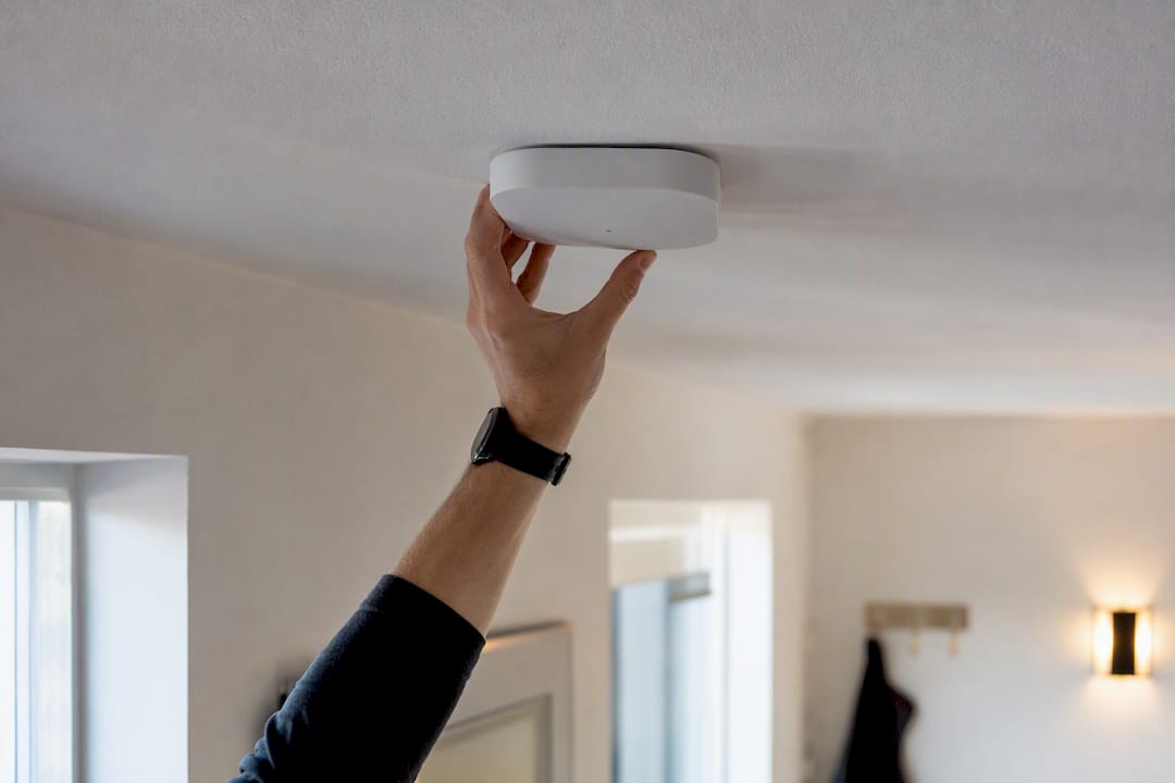 En person monterar en wifi-accesspunkt i taket